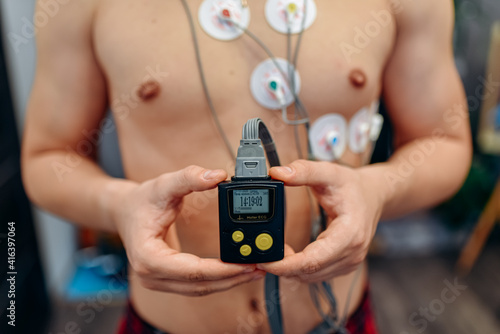 Heart electrocardiogram or monitoring using Holter for young patient. Male athlete does a cardiac stress test. wearing Holter monitor device for daily monitoring of an electrocardiogram.  photo