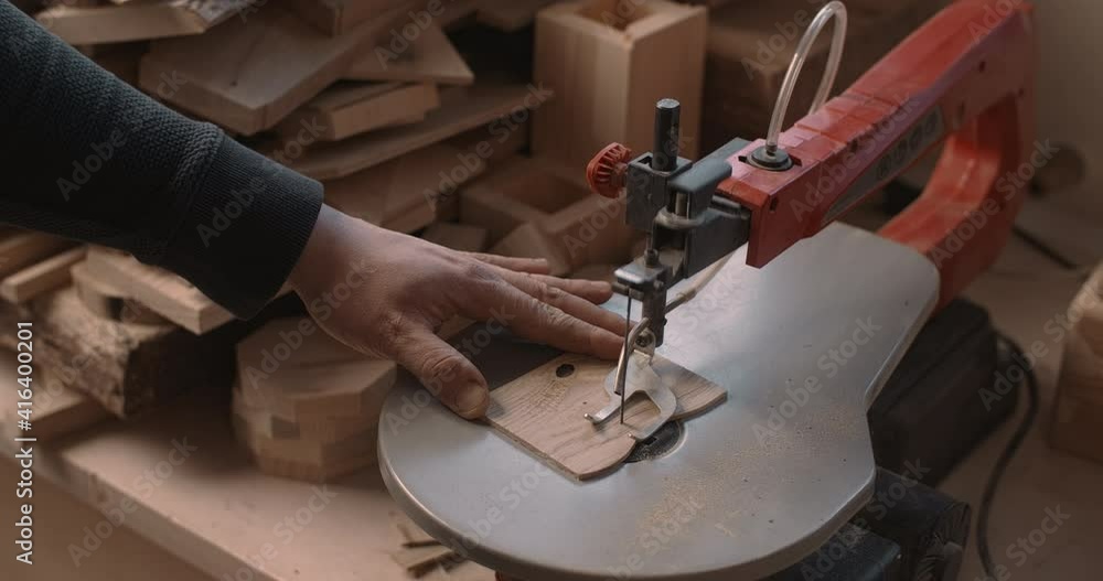 Woodworking at the workshop: carpenter uses automatic jigsaw and cuts small plywood parts, manufacturing of wooden products, master works with timber, 4k DCI 60p Prores 422 10 bit Woodworking at the workshop: carpenter uses automatic jigsaw and cuts small plywood parts, manufacturing of wooden products, master works with timber, 4k DCI 60p Prores 422 10 bit
