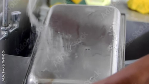 Male hands washing tray in restaurant kitchen sink