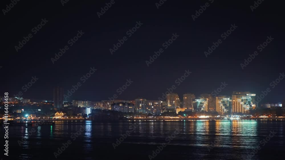 Panoramic view of Gelendzhik city resort seafront at night with illuminated modern buildings reflected in sea water. Panoramic view of Gelendzhik city resort seafront at night with illuminated modern buildings reflected in sea water.
