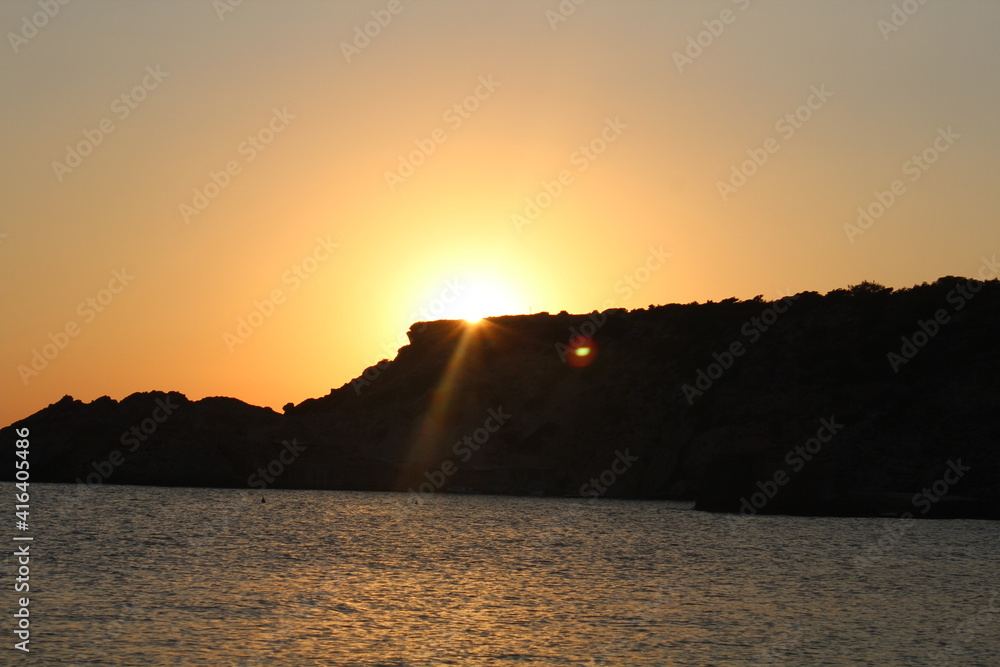 die Sonne geht mit einem Schein auf Ibiza unter