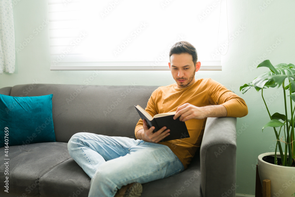 Smart man enjoying a novel during a leisure day at home