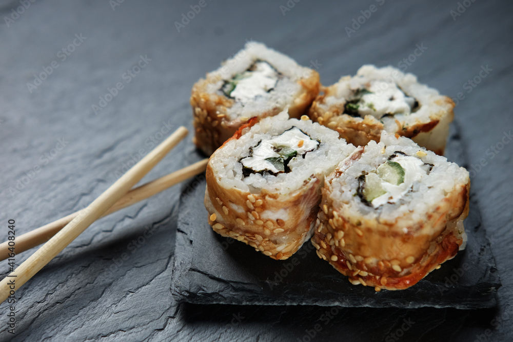 Sushi rolls with chopsticks on dark background Sushi rolls with chopsticks on dark background