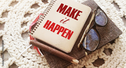 Make it happen message on the cover of spiral notebook with eyeglases and pen. Business motivation concept photo
