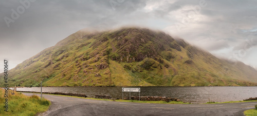 Road signs Leenaun and Louisburgh by a road. Beautiful scenery in the background. Mountains and low clouds and a lake. Connemara, Ireland. Nature background. Panorama image photo