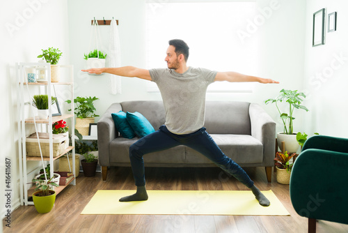 Hispanic man practicing a warrior 2 yoga pose at home