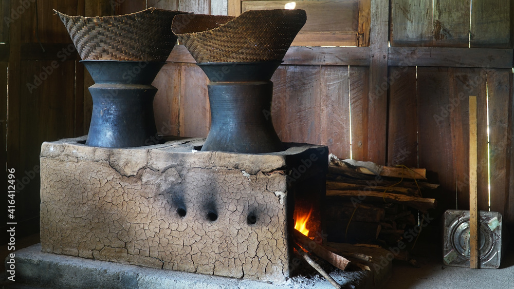 Traditional kitchen with firewood. There are two clay pans and a bamboo steamer on top. Classic kitchen of Indonesia