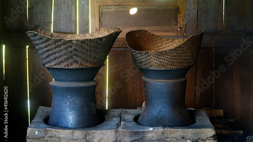 Traditional kitchen with firewood. There are two clay pans and a bamboo steamer on top. Classic kitchen of Indonesia