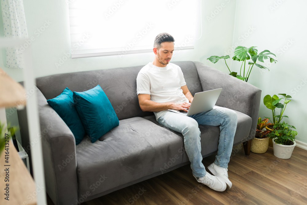 Man in his 30s doing online shopping in the living room