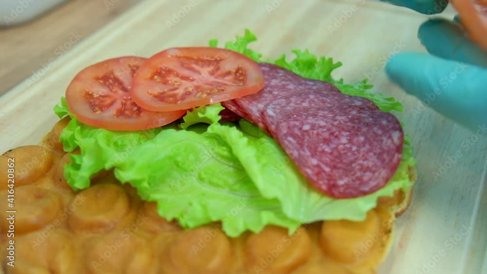 Chef makes hongkong waffle stuffed with vegetables salami sausage and salad Chef makes hongkong waffle stuffed with vegetables salami sausage and salad