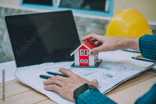 Worker working in office with laptop computer and work house design for building photo