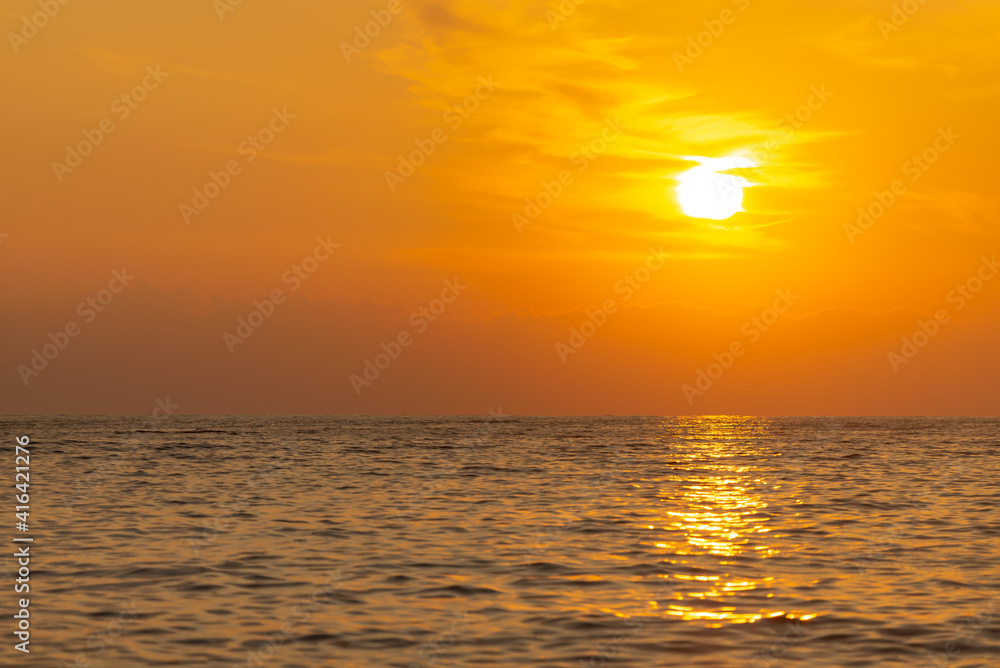 Yellow sunset from the low sun. Seashore with a sunset path on the waves.