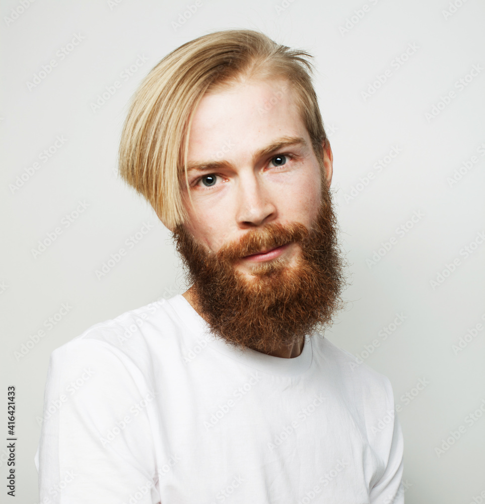 Headshot of attractive serious Caucasian male with thick ginger beard and trendy haircut, dressed in casual white t shirt, isolated over white background Headshot of attractive serious Caucasian male with thick ginger beard and trendy haircut, dressed in casual white t shirt, isolated over white background