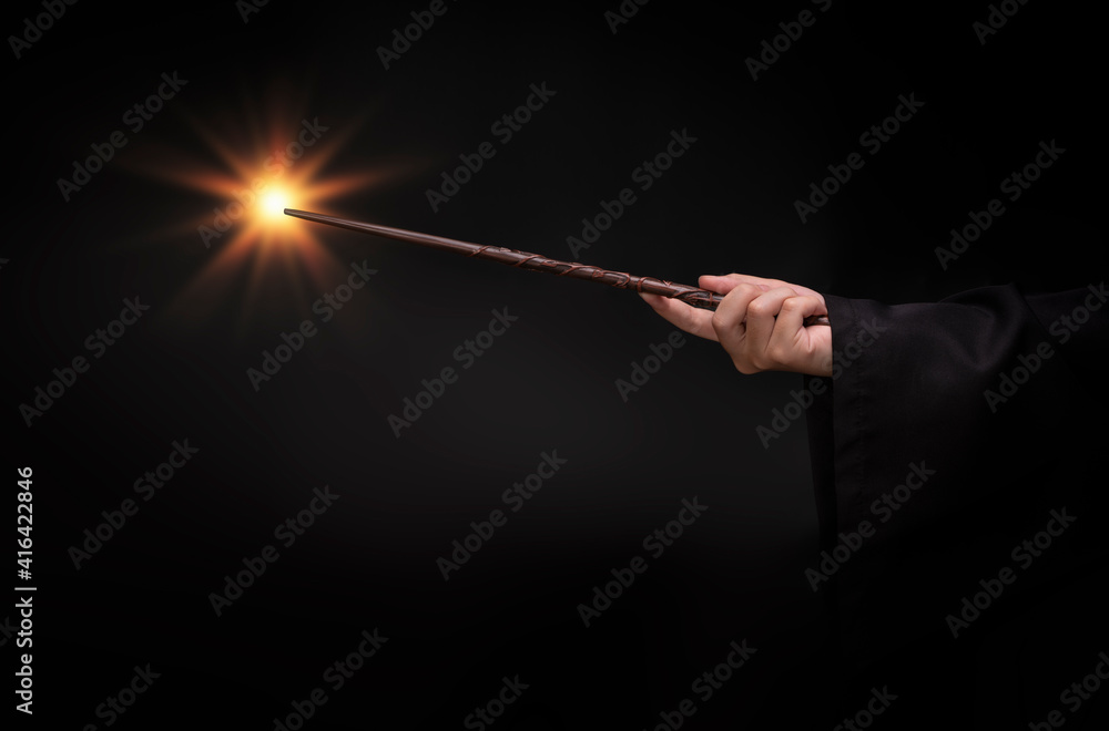 Naklejka premium Magic wand with sparkle, Miracle magical wand stick with light sparkle. Teens hand holding a wand wizard conjured up in the air.