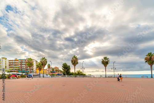 Early morning sunlight comes through the clouds along the Mediterranean sea coast of the Italian Riviera at Ventimiglia, Italy on market day.