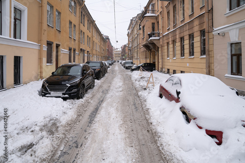 Parked cars covered with snow on an uncleaned snowy road after snowfall. Bad winter weather, increased precipitation and snow levels concept.  © DimaBerlin
