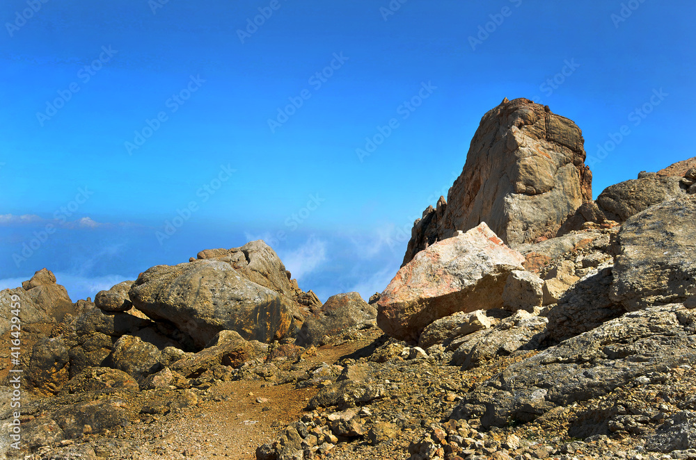 The steep cliffs in the mountains are granite against a blue sky with fog in the horizon