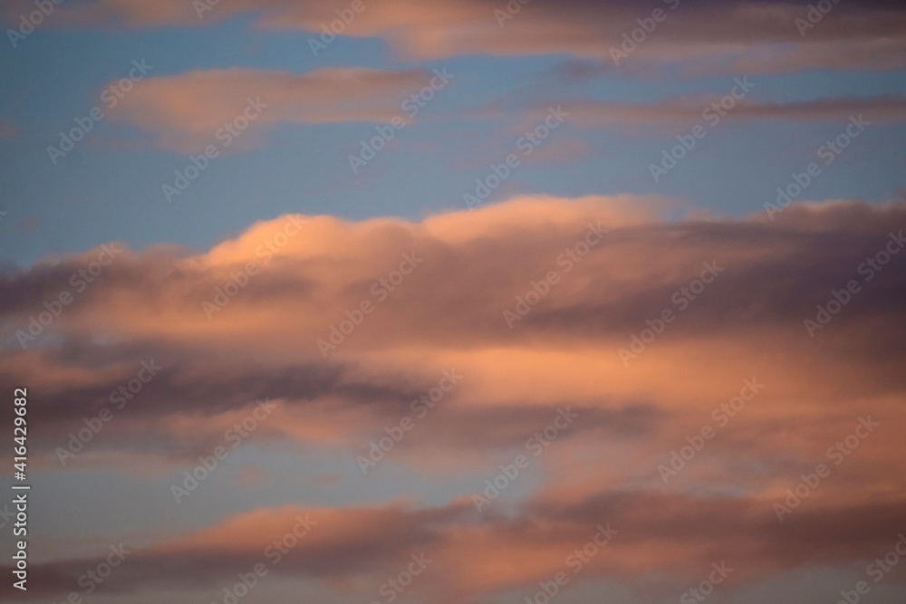 This photograph shows whimsical sunset clouds in a warm blue summer sky.