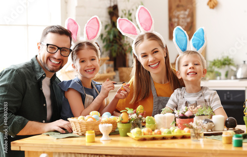 Canvas Print Happy family painting Easter eggs in light kitchen