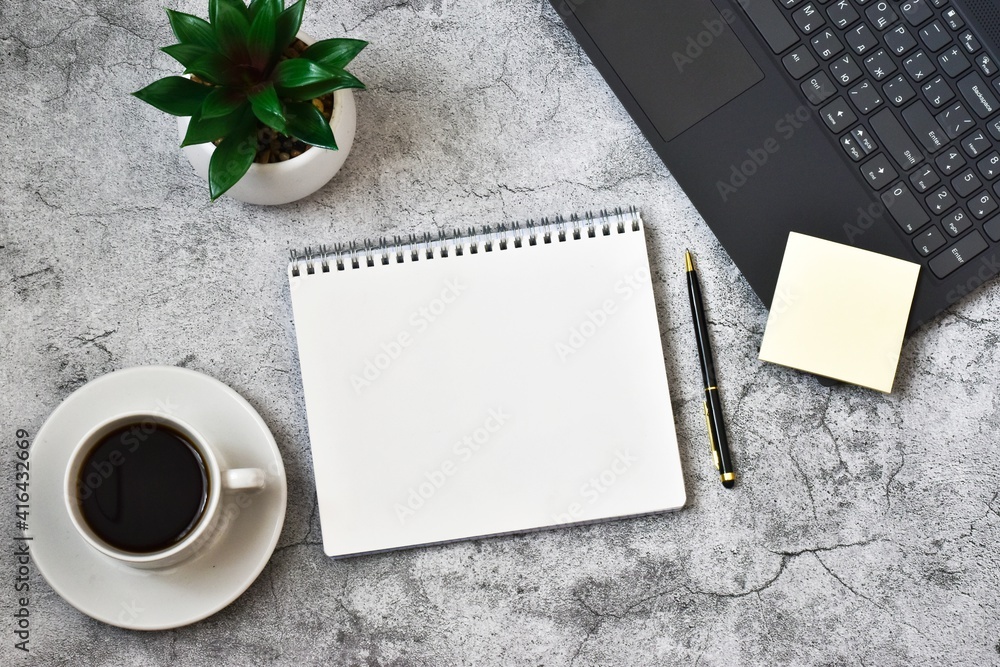 Notepad, laptop with cup coffee and pen on concrete grey background. Workplace. copy space, flat lay. Concept business and finance. Notepad, laptop with cup coffee and pen on concrete grey background. Workplace. copy space, flat lay. Concept business and finance.