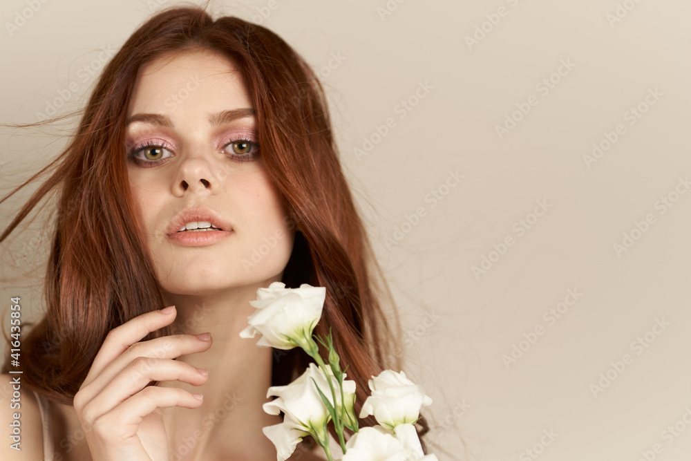 Happy woman with a bouquet of light flowers on a beige background naked shoulders model red hair beautiful face Happy woman with a bouquet of light flowers on a beige background naked shoulders model red hair beautiful face