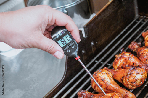Принти на полотні Gatineau, Quebec Canada - July 18, 2020: A food thermometer checking that chicken is being cooked correctly, safely on a barbecue along with prawns on a sunny day in the garden