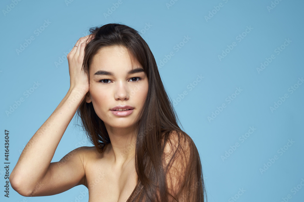 brunette with bare shoulders cosmetics close-up skin care blue background brunette with bare shoulders cosmetics close-up skin care blue background