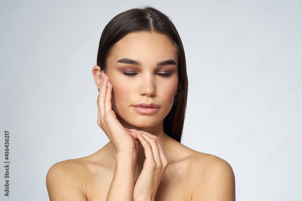 Obraz premium Woman with long hair bared shoulders clean skin body care light background