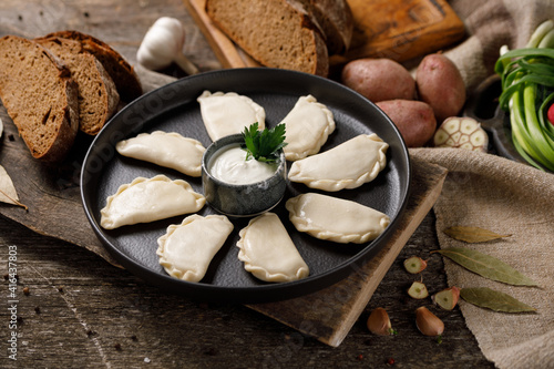 Appetizing traditional Russian dumplings, hand-made with potatoes. Still life on a wooden board. Close-up. photo