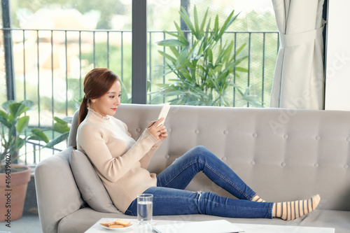 Happy millennial girl checking social media holding smartphone at home