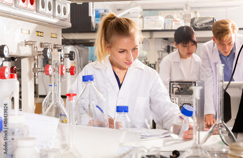 Portrait of European female scientist working with her colleagues in biochemical laboratory