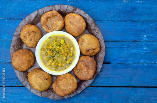 Khasta Kachori or Kachodi with Curried Yellow Peas or Ghugni Curry in a Leaf Plate Isolated  Blue Wooden Background with Copy Space, Indian Delicious Snack or Breakfast Food photo