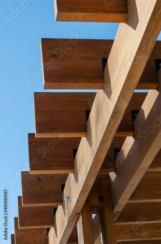 An abstract geometric composition of brown wooden planks against a blue sky.