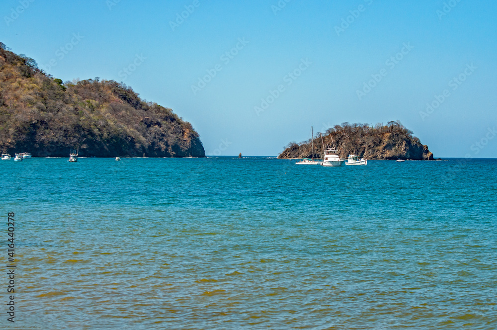 Boats are anchored in the bay with small islands in the background.