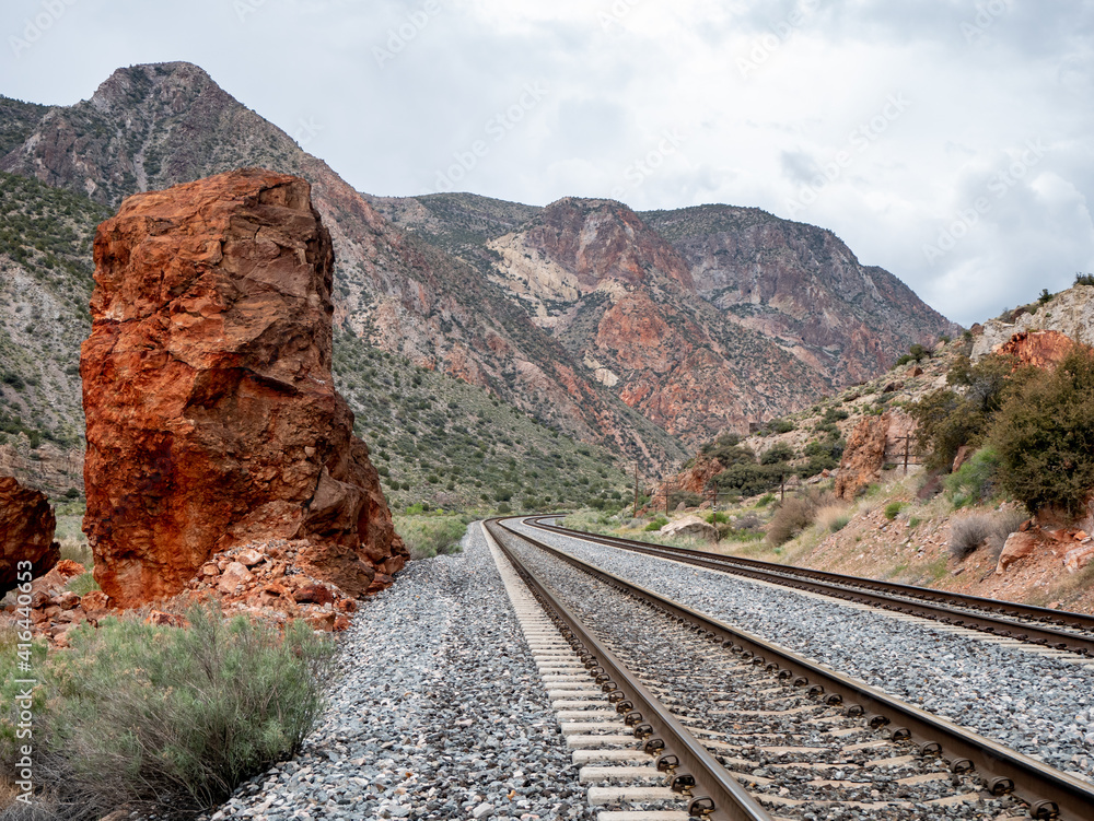 Tall vertical red boulder beside railroad tracks. Tall vertical red boulder beside railroad tracks.