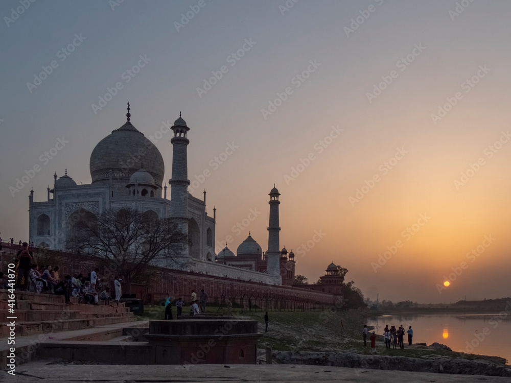 tourists watch the sun set behind the taj mahal and yamuna river in agra