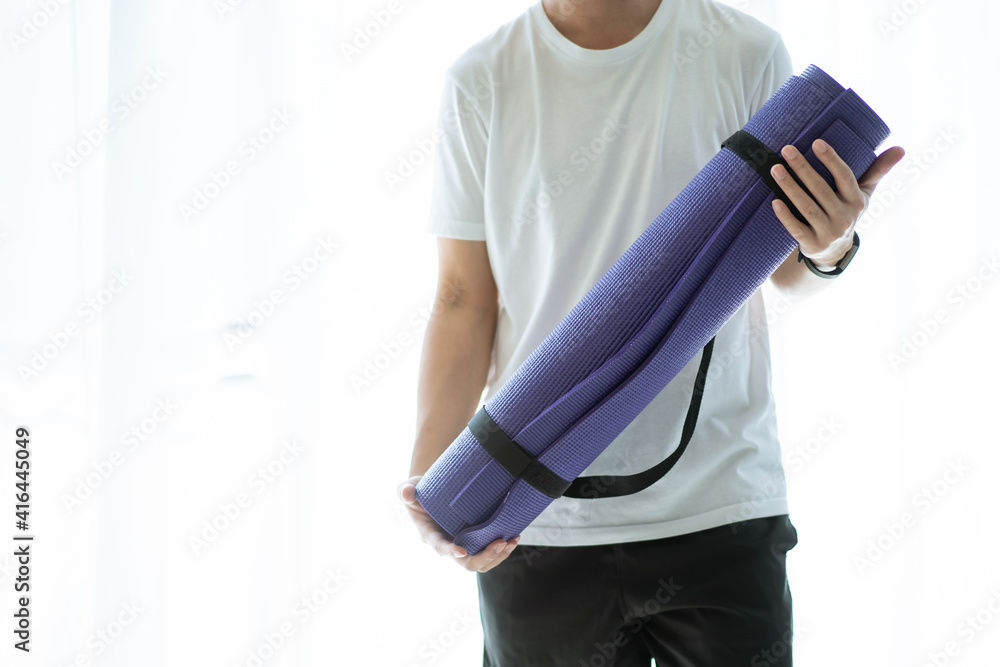 Unrecognizable Asian young man carrying a roll of yoga mat.