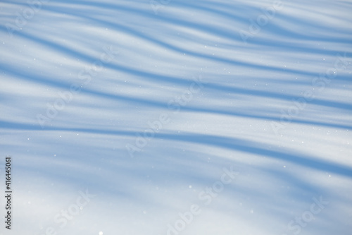 blue contrasting shadows on white snow on a bright sunny day, background