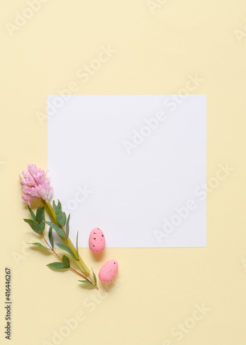 Fototapeta Naklejka Na Ścianę i Meble -  White invitation card mockup with eucalyptus branches, pink hyacinth and eggs on a yellow background.