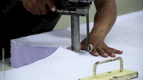 Factory worker cutting of fabric in factory. Used the razor machine for cutting fabrics in mass production.