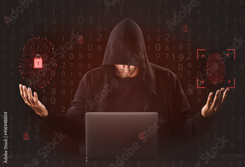 Professional male hacker with laptop on dark background photo