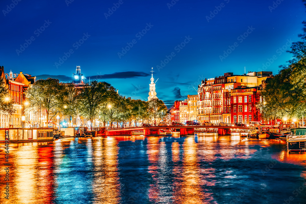AMSTERDAM, NETHERLANDS- SEPTEMBER 16, 2015: Famous Amstel river and night view of beautiful Amsterdam city. Boats, cars on street.