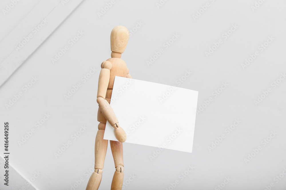 Wooden mannequin with blank poster on light background Wooden mannequin with blank poster on light background