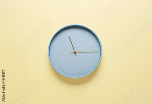 Stylish clock hanging on color wall