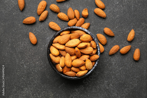 Bowl with healthy almonds on dark background