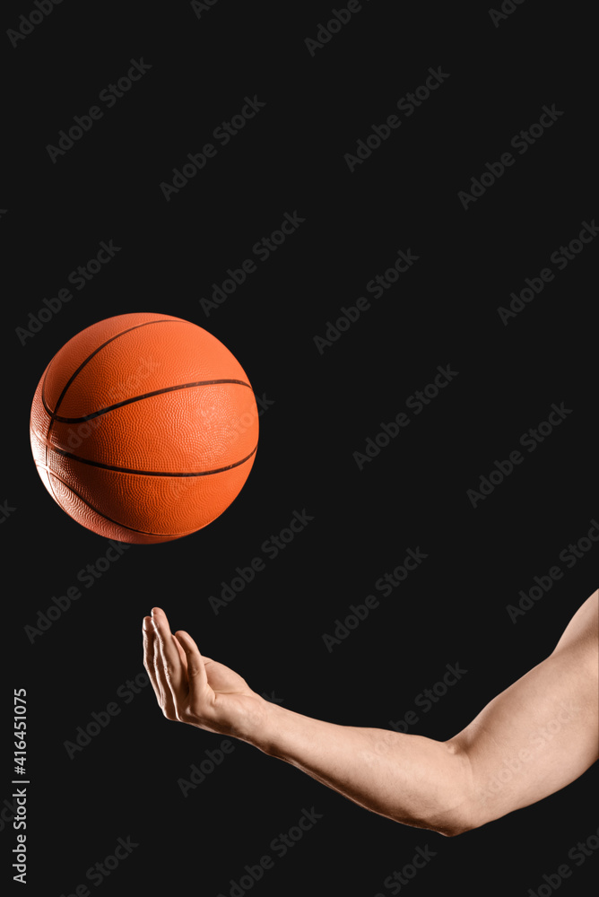 Hand of male basketball player with ball on dark background Hand of male basketball player with ball on dark background