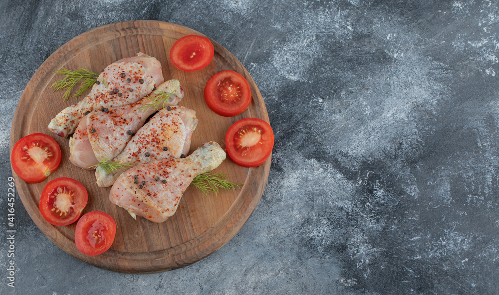 Raw chicken drumstick with tomato ready for cooking Raw chicken drumstick with tomato ready for cooking