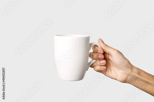 Hand with cup on light background