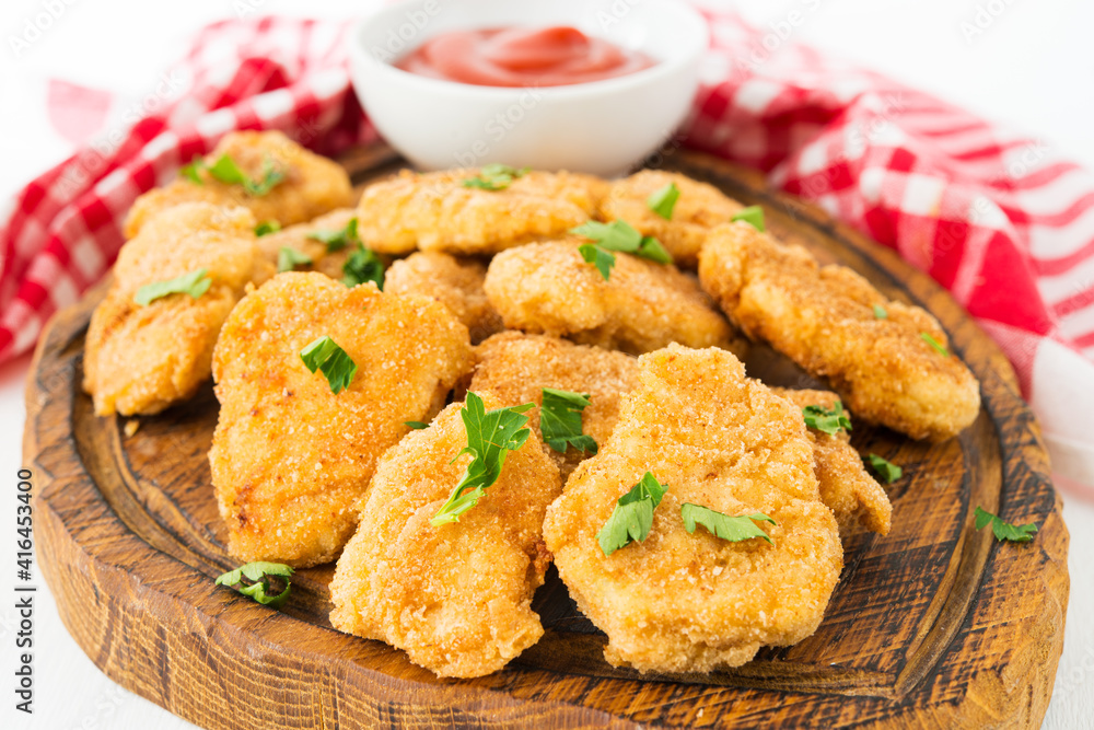 Homemade chicken nuggets with ketchup on a wooden board