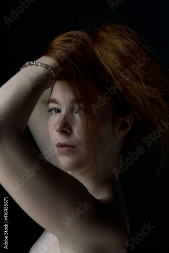 Ginger hair young white model holding her hair with black background